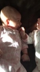 Newborn twin girl amused by crying sister